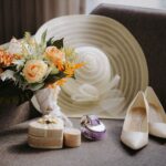 Bukiet ślubny, kapelusz i buty ułożone na sofie