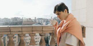 Jak urządzić balkon jako mini strefę relaksu i pracy w jednym Mężczyzna pracuje przy laptopie i pije kawę na miejskim balkonie